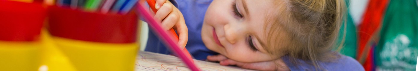 Girl aged 2 smiling with her head down scribing